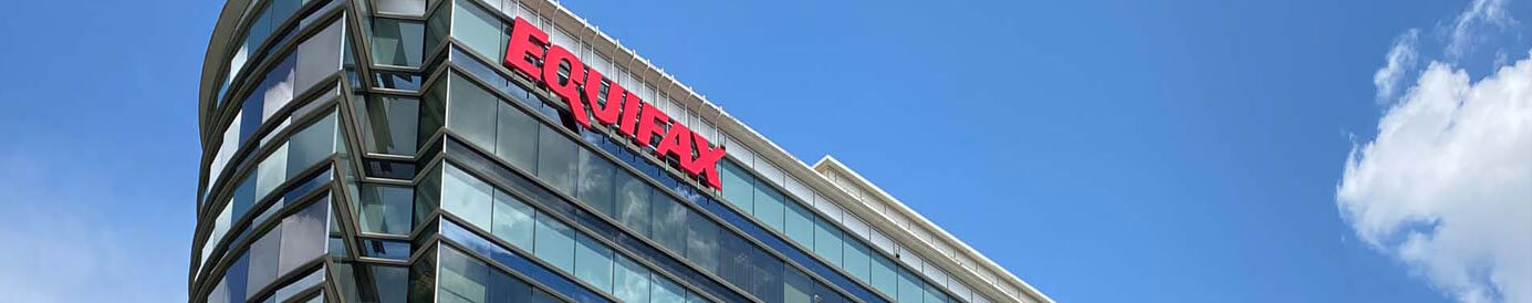 A contemporary styled office building with a blue sky behind it. A red Equifax logo sign is placed near the top left.