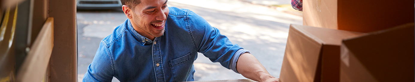 A man packs boxes into the back trunk of a moving van.
