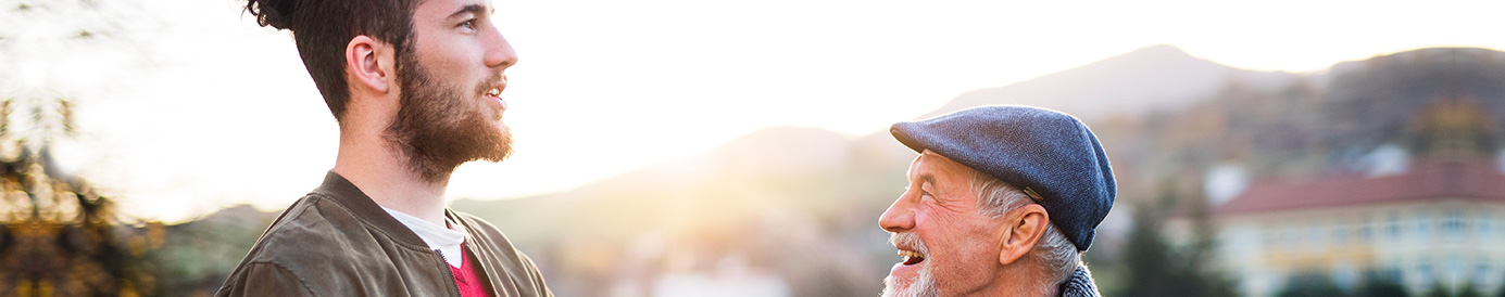 A father and son stand on a hill together. The son has his hand on the father’s shoulder.
