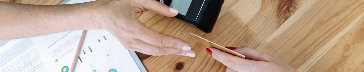 Customer handing her debit card to a cashier at the register to complete a purchase.