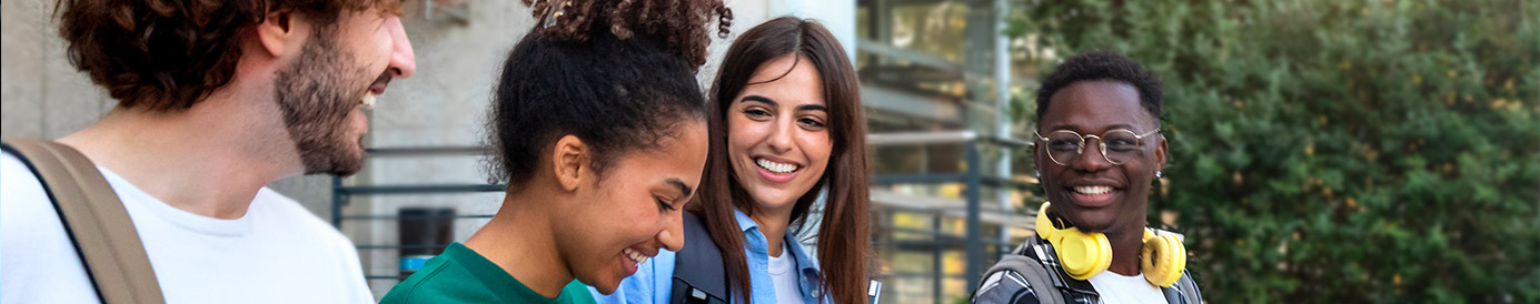 Four college students walk together outside of a building. They are walking down a flight of stairs.