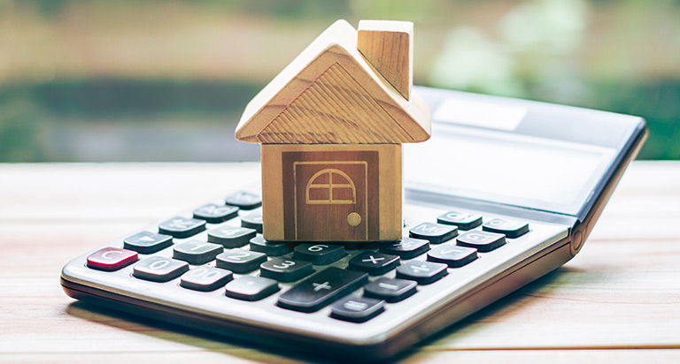 Tiny wooden house on top of a calculator