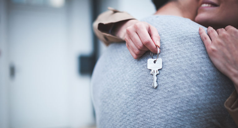 A couple hugging after buying their first home