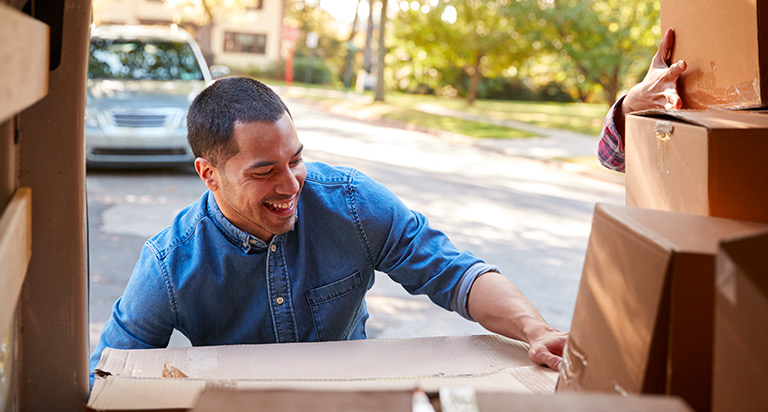 A man packs boxes into the back trunk of a moving van.