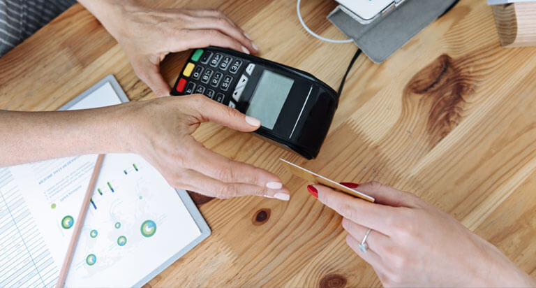 Customer handing her debit card to a cashier at the register to complete a purchase.